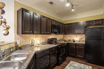Kitchen with black appliances at Grand Villas at Cinco Ranch, Katy, Texas